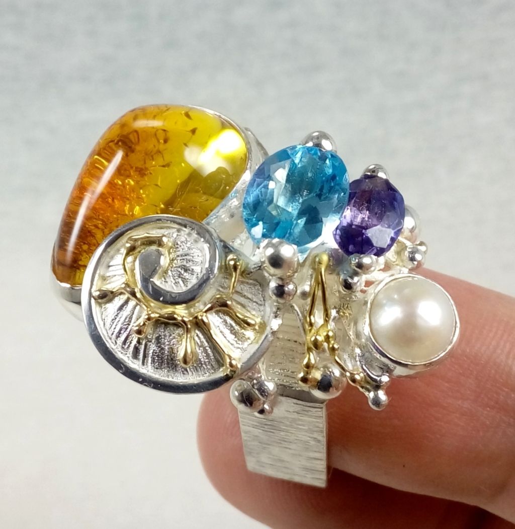 Gregory Pyra Piro håndlaget firkantet ring 4822, smykker solgt i kunst og håndverksgallerier, smykker laget av kunstner, håndlagde smykker laget av håndverkere, unik form firkantet ring, smykker i blandet metall laget av gull og sølv, håndlaget firkantet ring med fasetterte edelstener og rav, håndlaget firkantet ring med ametyst og blå topas, ring med ametyst og rav, ring med blå topas og rav