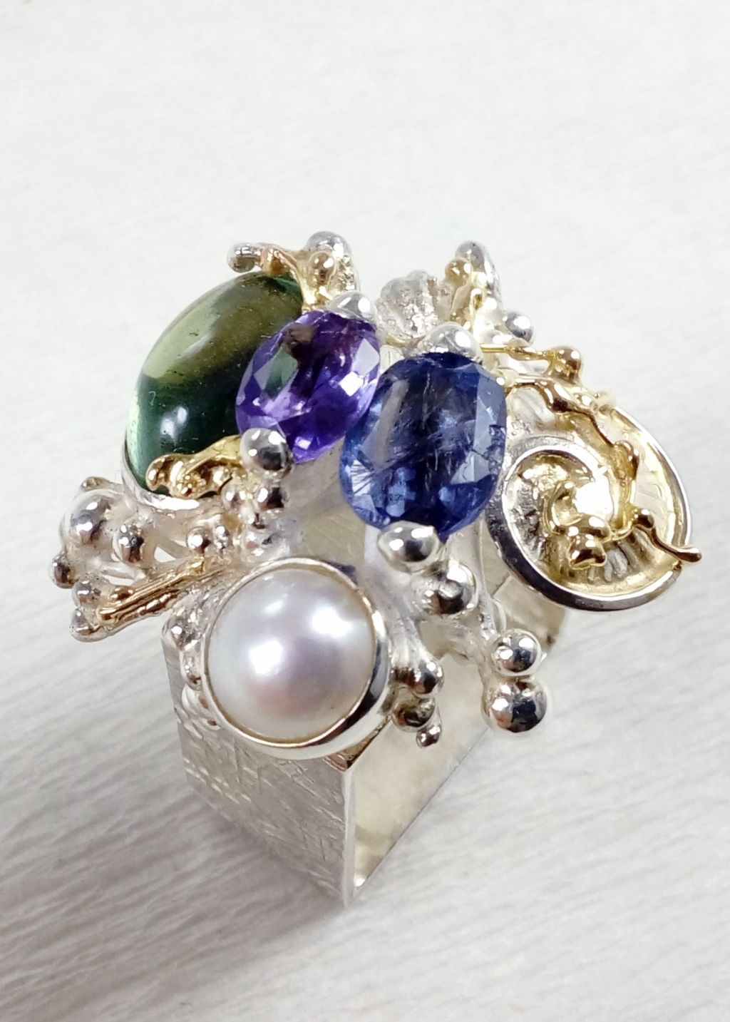 jewelry made from gold and silver, jewelry with color stones, jewelry with real pearls, gregory pyra piro square ring 4821, where to find an auction house with gemstones and jewellery, fine craft gallery handcrafted ring for sale, sterling silver and 14 karat gold ring, ring with amethyst, fluorite, iolite and pearl, one of a kind handcrafted ring, where to find auctions with fine art and designer jewellery, where to buy gregory pyra piro jewelry right now
