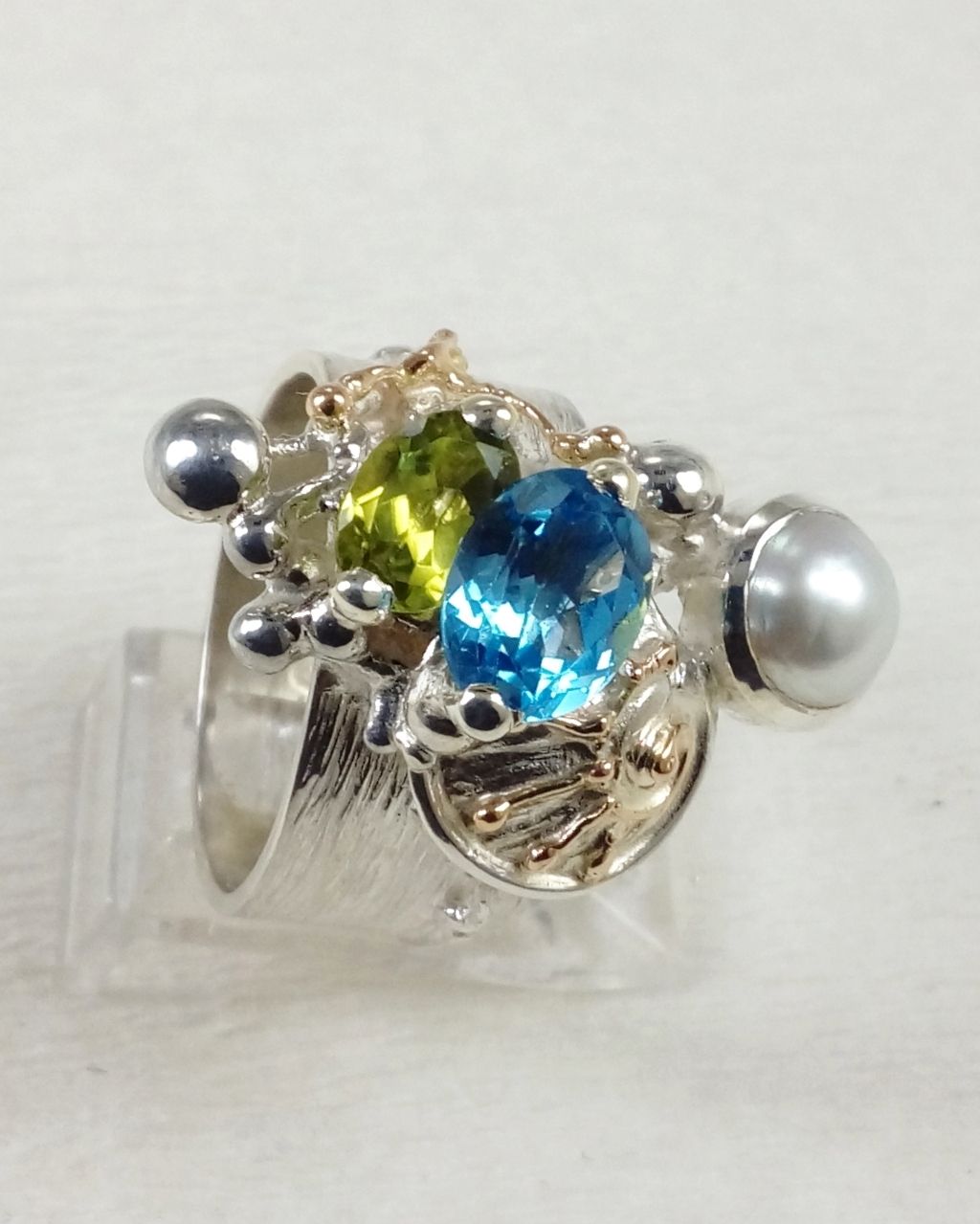 Gregory Pyra Piro prsten 3025, prsten s modrým topásem a peridotem, prsten s fazetovanými drahokamy a perlami, prsten ručně vyráběný řemeslníkem, prsteny prodávané v galeriích, šperky s doručením do Brna, šperky s doručením do Ostravy, šperky s doručením v Čechách