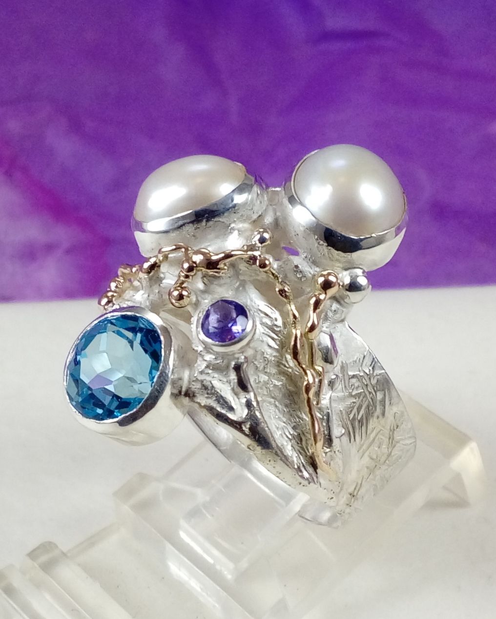 skulpturaler Ring Artikelnummer 7320, Gregory Pyra Piro skulpturaler Ring, Ring mit blau Topas und Amethyst, Ring mit Amethyst und Perle, Ring mit Blau Topas und Perle, Auktionen mit Designerschmuck und Sammlerstücken, online einzigartigen Schmuck kaufen, wo man hochwertigen handgefertigten Schmuck kaufen kann, Künstler und Hersteller unterstützen, feines Handwerk unterstützen, feines Handwerk online kaufen, hochwertigen einzigartigen Schmuck online kaufen, Kunsthandwerk und Kunstwerke online kaufen, Schmuck in Kunstgalerien verkauft, Ringe von Handwerkern handgefertigt, Ringe in Kunstgalerien verkauft