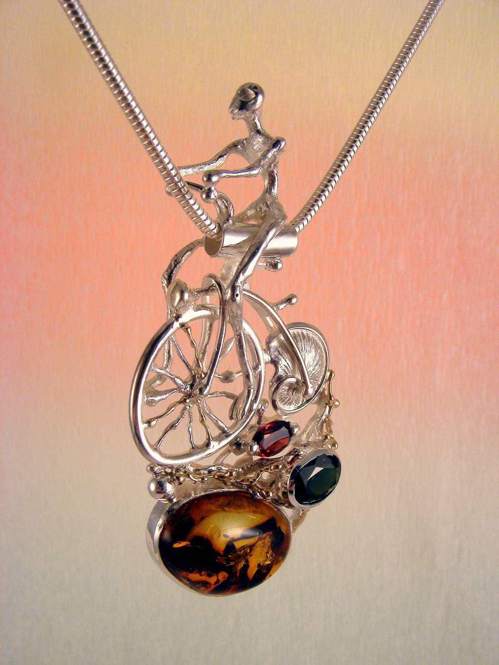 gregory pyra piro sculptural pendant 4287, artists during lockdown making handcrafted jewellery, makers during lockdown who make handcrafted jewellery, galleries during lockdown with handcrafted jewellery, historical high wheel bicycle sculptural pendant, pendant with bicycle that has shell wheel, penedant with facted gemstones and amber, pendant with green tourmaline and garnet, jewellery with home delivery in Galway, jewellery with home delivery in Dublin, jewellery with home delivery in Belfast, silver and gold jewelry with gemstones for women