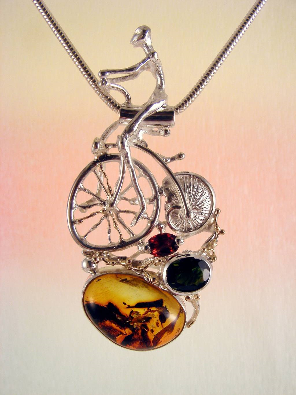 gregory pyra piro sculptural pendant 4287, artists during lockdown making handcrafted jewellery, makers during lockdown who make handcrafted jewellery, galleries during lockdown with handcrafted jewellery, historical high wheel bicycle sculptural pendant, pendant with bicycle that has shell wheel, penedant with facted gemstones and amber, pendant with green tourmaline and garnet, jewellery with home delivery in Galway, jewellery with home delivery in Dublin, jewellery with home delivery in Belfast, silver and gold jewelry with gemstones for women